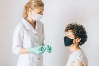 Profissional de saúde prepara uma vacina para uma paciente numa unidade clínica.