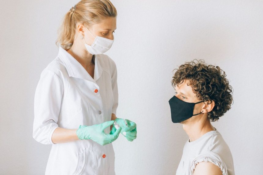 Profissional de saúde prepara uma vacina para uma paciente numa unidade clínica.