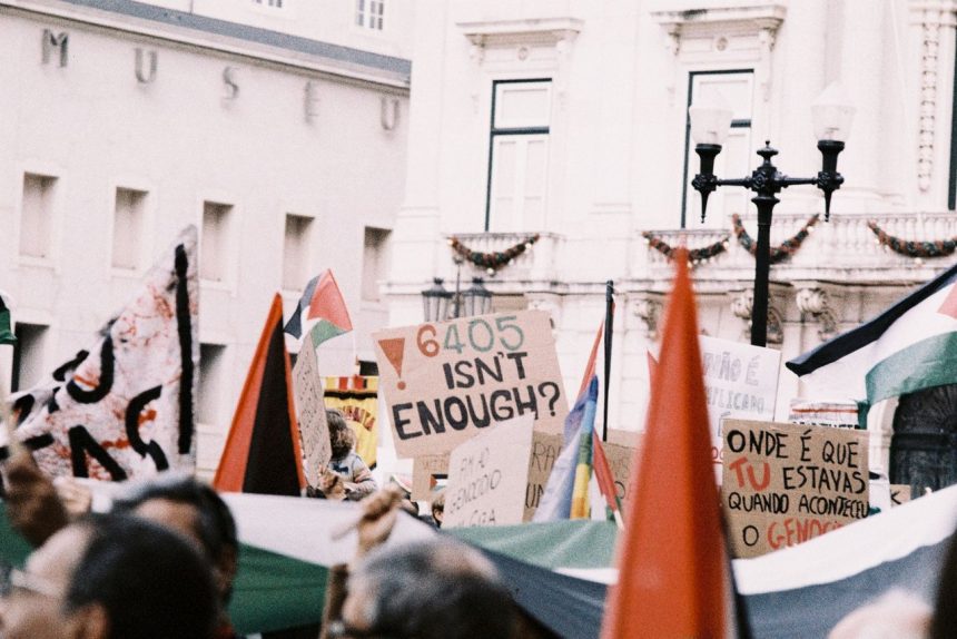 Manifestantes erguem cartazes e bandeiras durante um protesto numa rua de Lisboa.