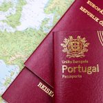 Passaportes português e austríaco sobre um mapa da Europa, representando mobilidade e documentação migratória.